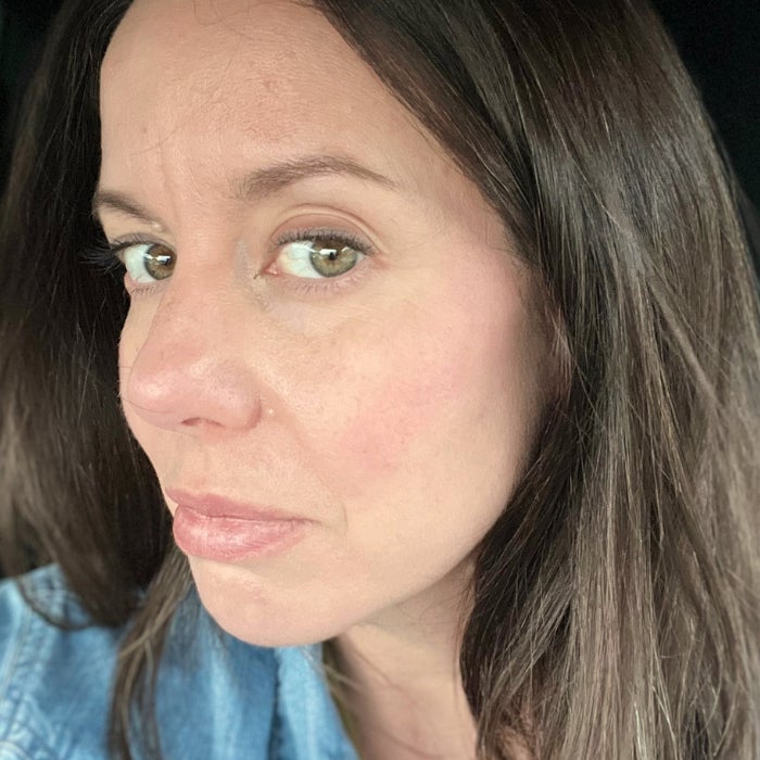 A profile view of a woman's face wearing PATRICK TA Major Headlines Double-Take Crème & Powder Blush Duo against a natural background