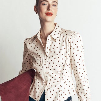 Boden; a woman wearing a polka dot blouse from Boden against a neutral background