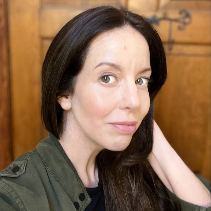 A slightly profile view of a woman's face against a brown background