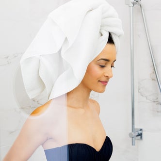 A woman with a towel wrapped around her hair against a natural background