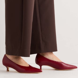 Quince; a close up of a woman's lower legs and feet wearing Quince Italian Leather Pointed Toe 40mm Kitten Heel Pump against a white background