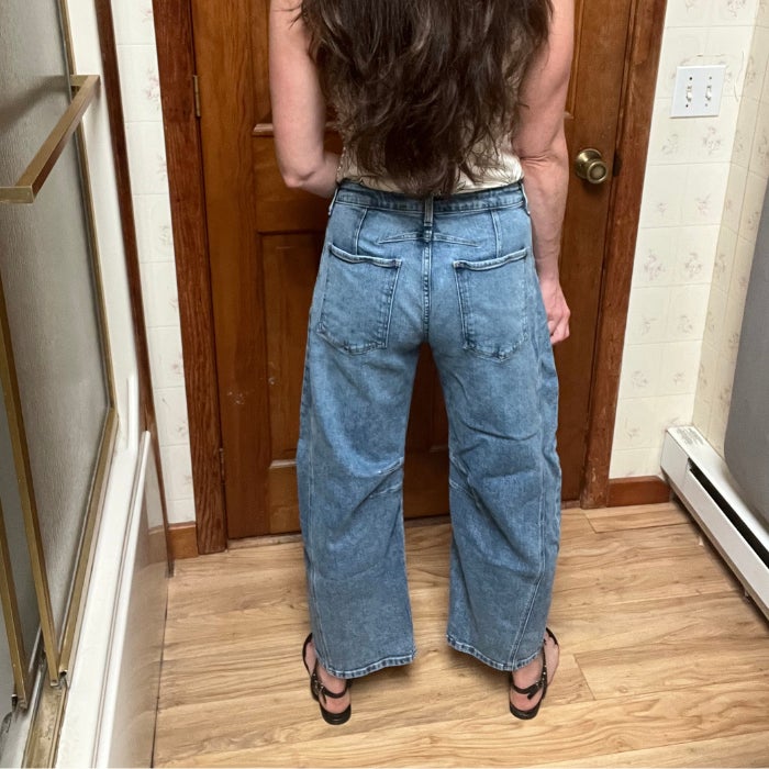 A view of the back of a woman wearing Kut From The Kloth Ashlyn Barrel Jeans against a natural background