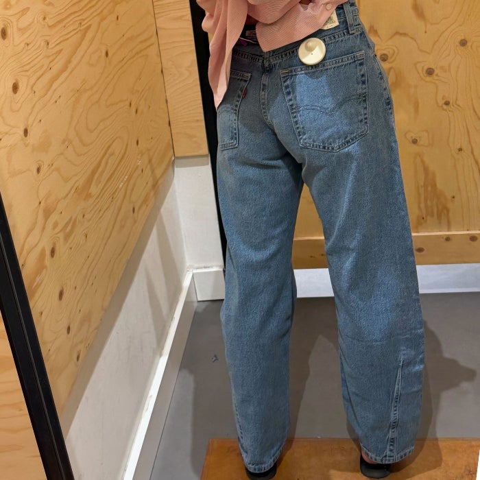 A back view of Anastasia Bilzhause wearing light wash Levi's Cinch Barrel Jeans in a wood paneled dressing room