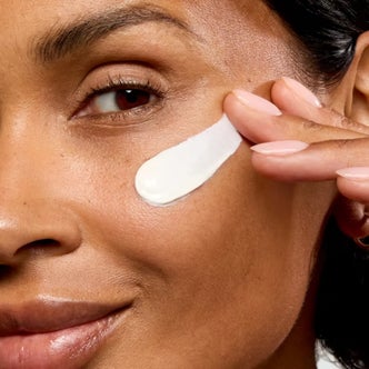 Target; a woman applying No7 Lift & Luminate Triple Action Fragrance Free Day Cream with SPF 30 to her face