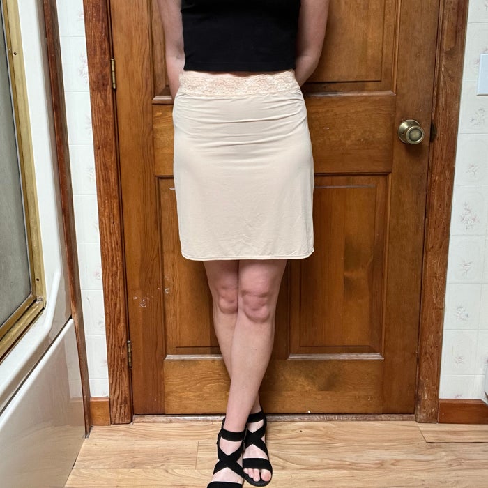 The lover half of a woman wearing Jockey Ultralight Smoothing Half Slip against a natural background