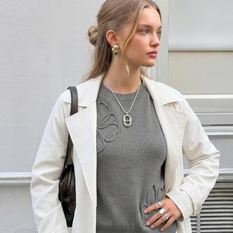Amazon; a woman wearing a gray floral sweater and white jacket against a natural background