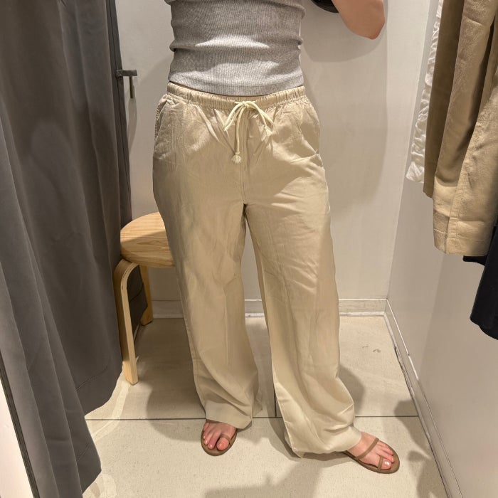 A front view of the bottom half of a woman wearing UNIQLO Linen Blend Easy Pants against a natural background