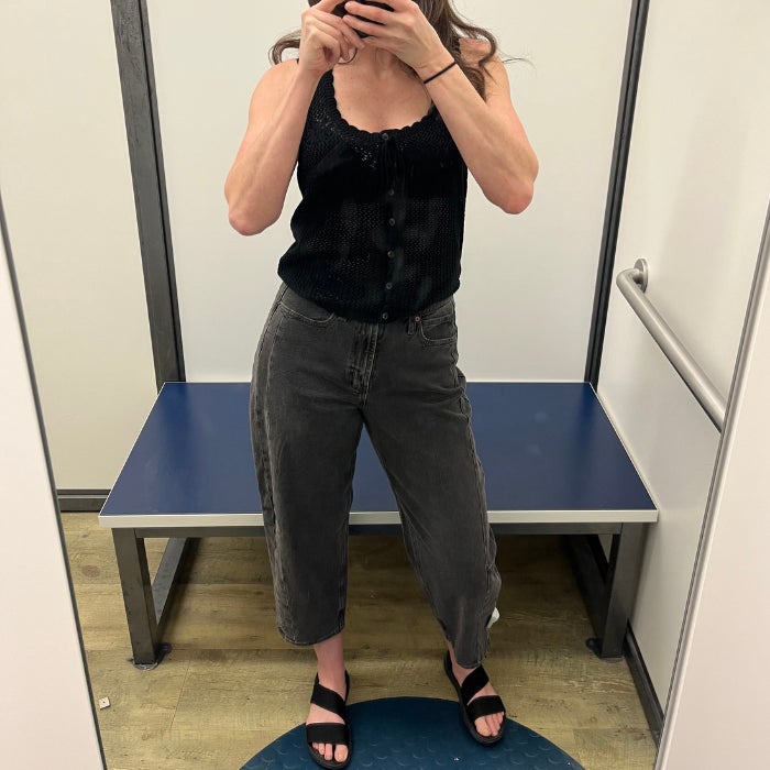 Brittany Brainard wearing gray Old Navy High Waist Ankle Barrel Jeans with a black tank top in a white dressing room.