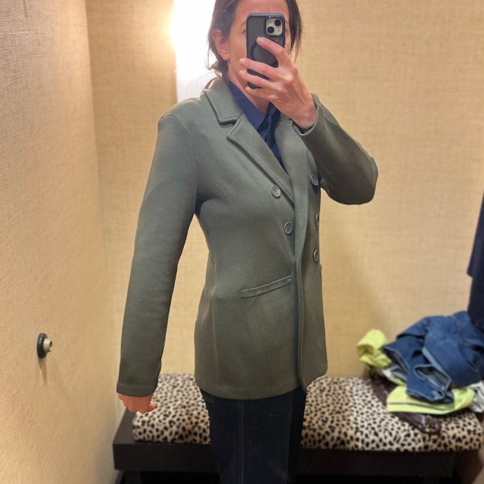 a woman wearing a green sweater blazer against a natural background
