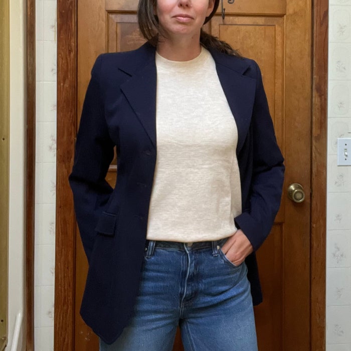 a woman wearing an ANRABESS Long Sleeve Lightweight Sweater under a navy blue jacket against a natural background