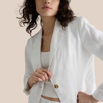 Quince; A woman wearing Quince 100% European Linen Structured Blazer in white against a beige background