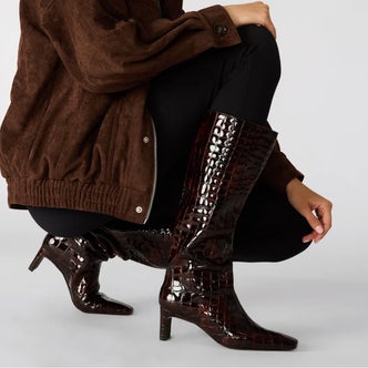 Steve Madden; a woman wearing Steve Madden Jendi Tortoise Crocodile against a light gray background