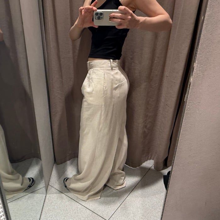 The side view of the bottom half of a woman wearing Zara Wide Leg Linen Pants against a natural background