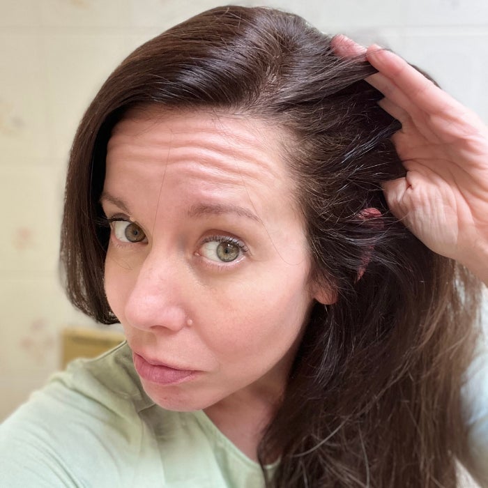 Brittany running her fingers through her hair against an off white background