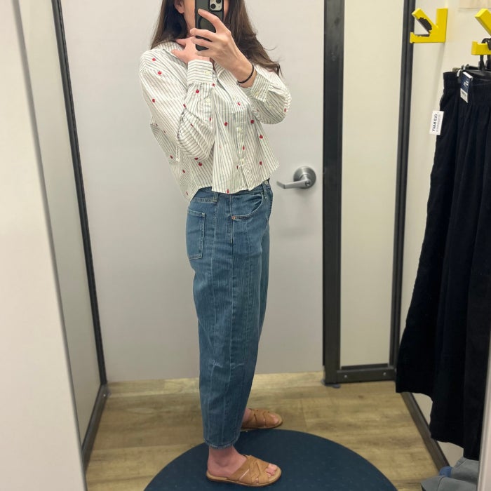 A profile view of a woman wearing Old Navy High-Waisted Barrel Ankle Jeans against a natural background