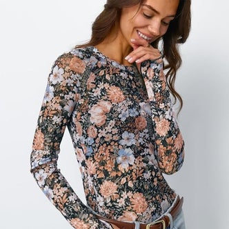 Amazon; a woman wearing a floral sheer mesh long sleeve tee against a neutral background