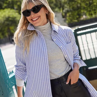 a woman wearing a turtleneck under a button down shirt against a natural background