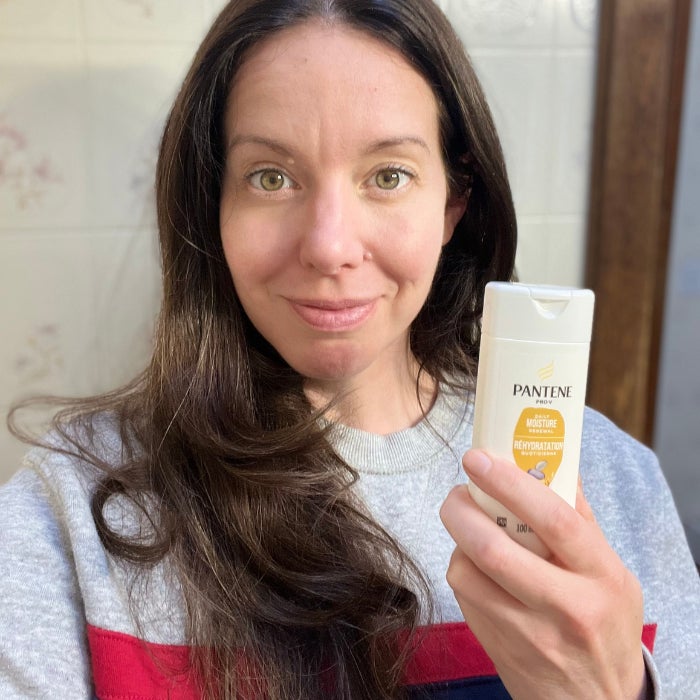 Brittany holding a bottle of Pantene Pro-V Daily Moisture Renewal Shampoo against a natural background