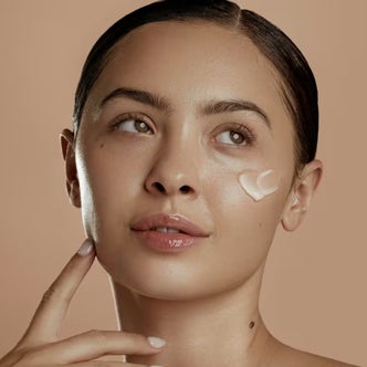 Ulta; a woman's face with a dallop of DIME Restorative Night Cream on her cheek against a tan background