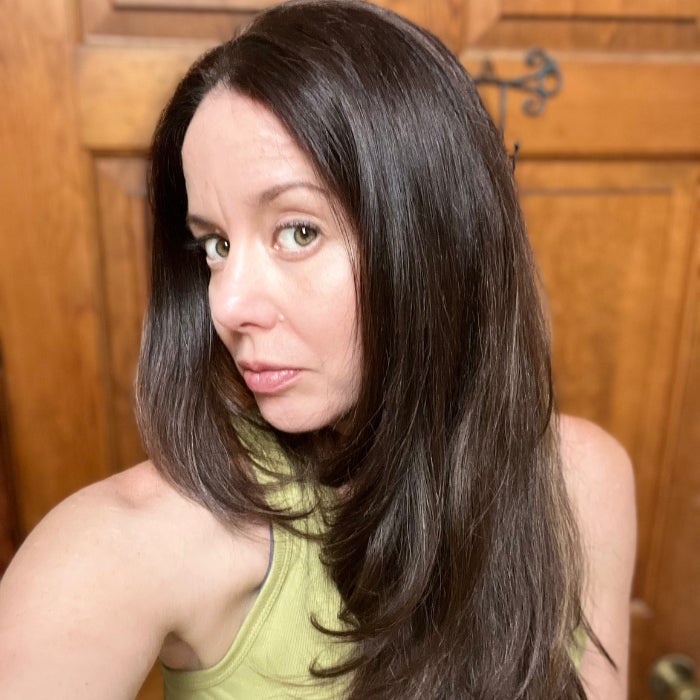 A woman's head with smooth, full looking hair against a natural background