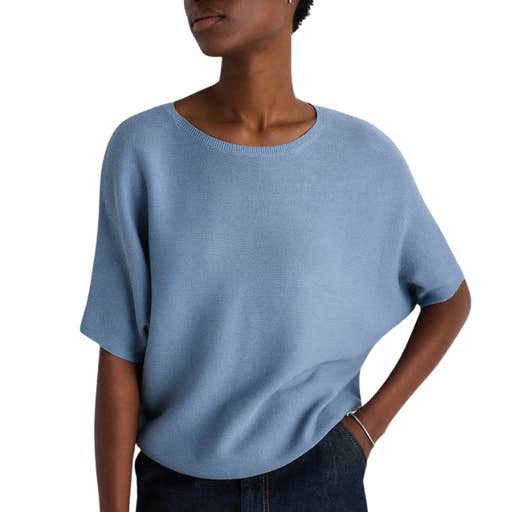 A woman wearing Quince Lightweight Cotton Cashmere Link-Stitch Dolman Sweater against a white background