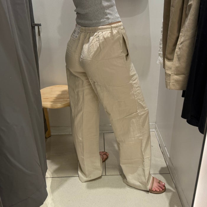 A side view of a woman wearing UNIQLO Linen Blend Easy Pants against a natural background