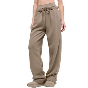 A person wearing light brown Alo Yoga Accolade Straight Leg Sweatpants against a white background