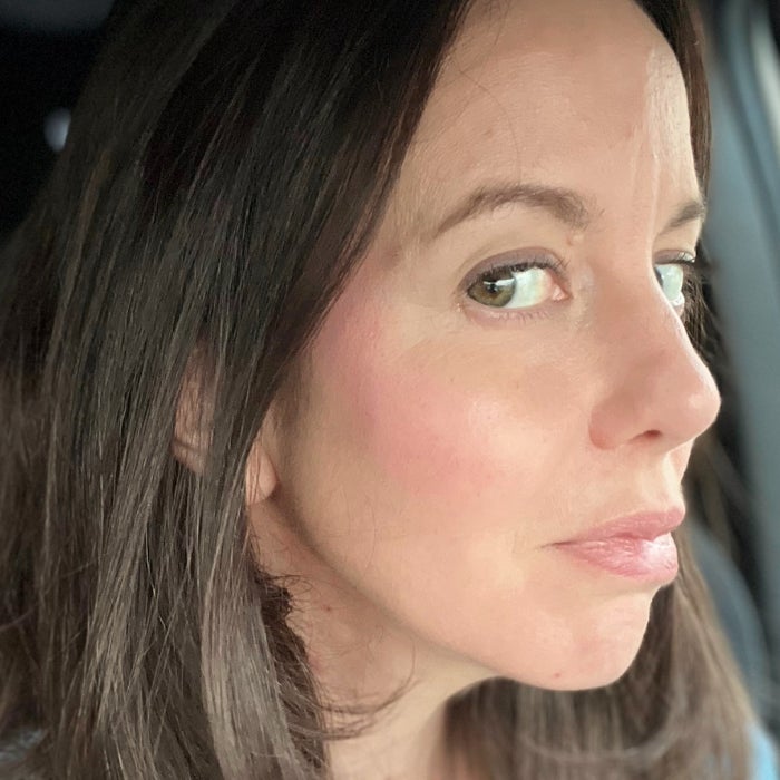 A profile view of a woman's face after applying Rare Beauty Soft Pinch Liquid Blush against a natural background